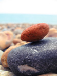 Two balanced rocks contrast a sea of stones under a blue sky