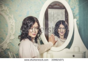 stock-photo-beautiful-woman-in-the-mirror-reflected-the-smiles-magically-in-retro-interior-339921071