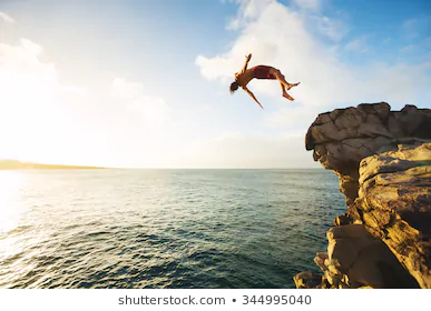 cliff-jumping-into-ocean-sunset-260nw-344995040